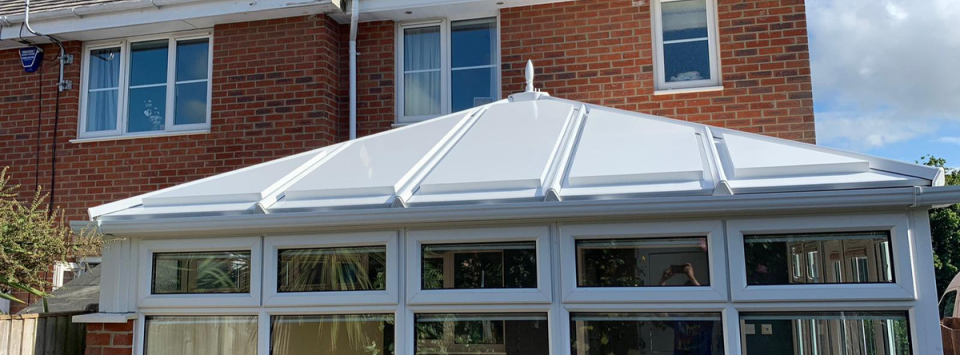 A Green Space UK conservatory roof with white panels backing onto a garden